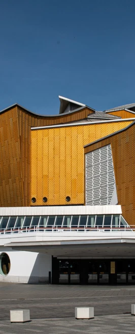 Exterior view of a strikingly modern yellow and grey building in Berlin, featuring bold geometric shapes and angles. Exterior view of a strikingly modern yellow and grey building in Berlin, featuring bold geometric shapes and angles.